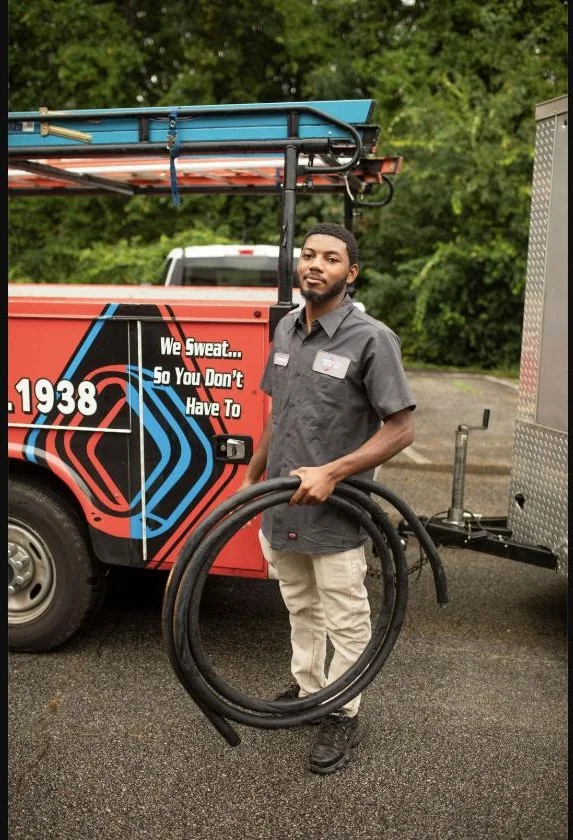 Absolute Best Air team member holding coiled service tubing beside a branded truck