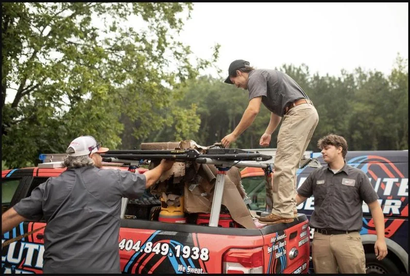 Absolute Best Air team members organizing equipment on a branded service truck